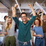 Was Teams heute wirklich motiviert – und wie man das umsetzt easyVSOP virtuelle Mitarbeiterbeteiligung VSOP Vertrag easyVSOP Team Bild alle haben die Hände nach oben gestreckt und lachen