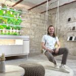 Wie nah kann dir Natur sein, ohne dass du das Haus verlässt? LIROGA indoor pflanzen Gründer Stefan Kuhnert vor Indoor-Garten im hängestuhl sitzend