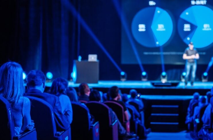 Startup Events Herbst 2025: Top Gründer-Termine in Europa Publikum auf einem Event auf der Bühne ist ein sPSrecher blaue Beleuchtung