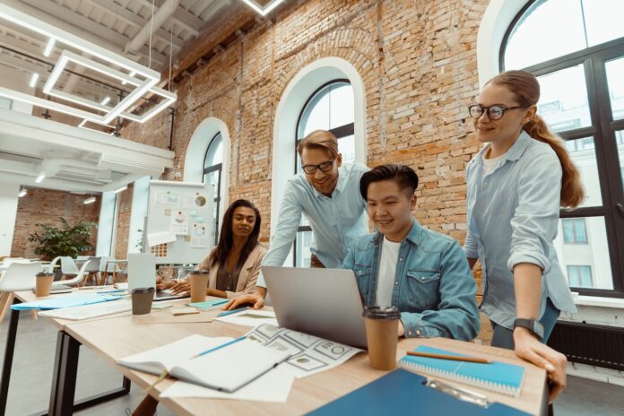 nxtgn-startup-factory-baden-wuerttemberg Gründer Team an einem großen Tisch mit Lapptop und Unterlagen beim Brainstorming
