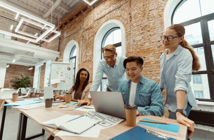 nxtgn-startup-factory-baden-wuerttemberg Gründer Team an einem großen Tisch mit Lapptop und Unterlagen beim Brainstorming