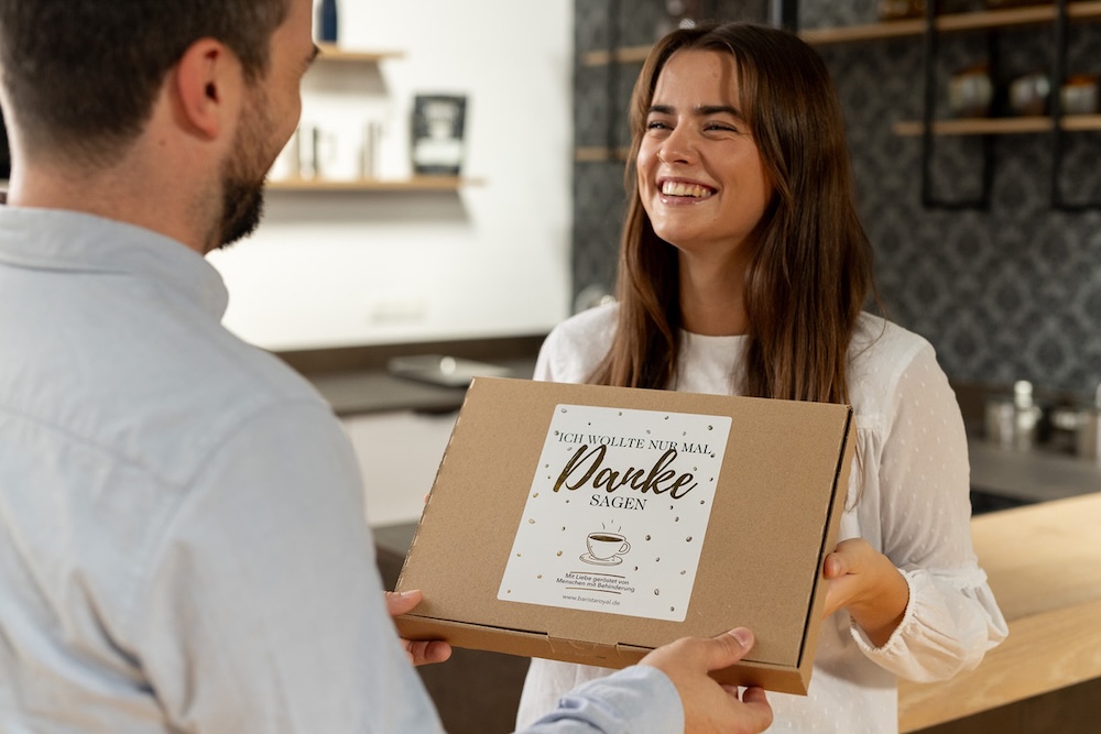 Barista Royal Geschenk Übergabe Frau übergibt Mann das Paket - Mood Bild