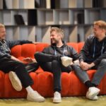 Wie verändert eine einzige Idee die Art, wie wir Genuss heute verstehen? RumX – Die Rum App für Rum Bewertungen.Team Bild sitzend auf einem roten sofa