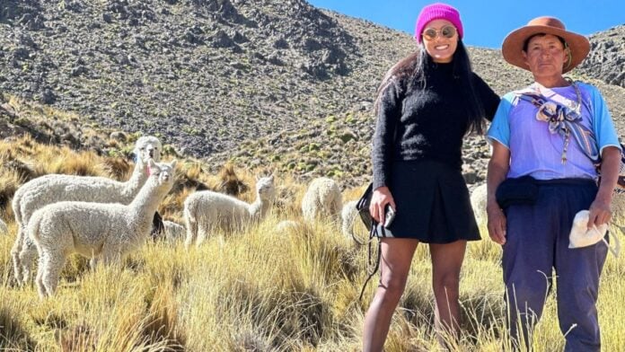 Alpaca MGO: Alpakafaser und Mode aus Peru Gründerin Maggie Garcia mit Alpakas im Hintergrund