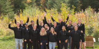 Aampere Finanzierung: Startup sammelt 4,2 Millionen Euro für E-Auto-Plattform ein Aampere Finanzierung Das Aampere Team steht nach der erfolgreichen 4,2 Mio. Euro Finanzierung auf einer Wiese vor einer Hecke.