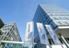 amber entwickelt KI für Unternehmenswissen und erhält sieben Millionen Euro für Wachstum. Drei Millionen Euro investiert die NRW.BANK in das Start-up. NRW.BANK Gebäude in Düsseldorf mit Fahnen und blick nach oben entlang des Gebäudes!