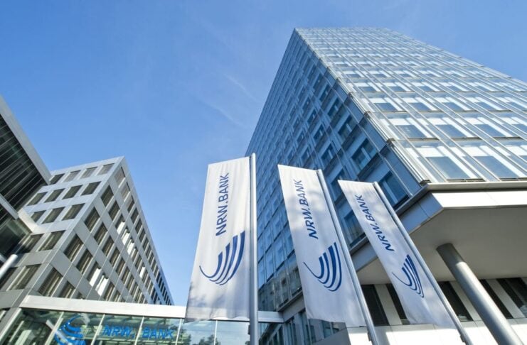 amber entwickelt KI für Unternehmenswissen und erhält sieben Millionen Euro für Wachstum. Drei Millionen Euro investiert die NRW.BANK in das Start-up. NRW.BANK Gebäude in Düsseldorf mit Fahnen und blick nach oben entlang des Gebäudes!
