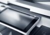 Günstige Toner für den Laserdrucker: Der Einkaufs-Check. Nahaufnahme eines modernen Druckers mit Touchscreen in einem professionellen Büro